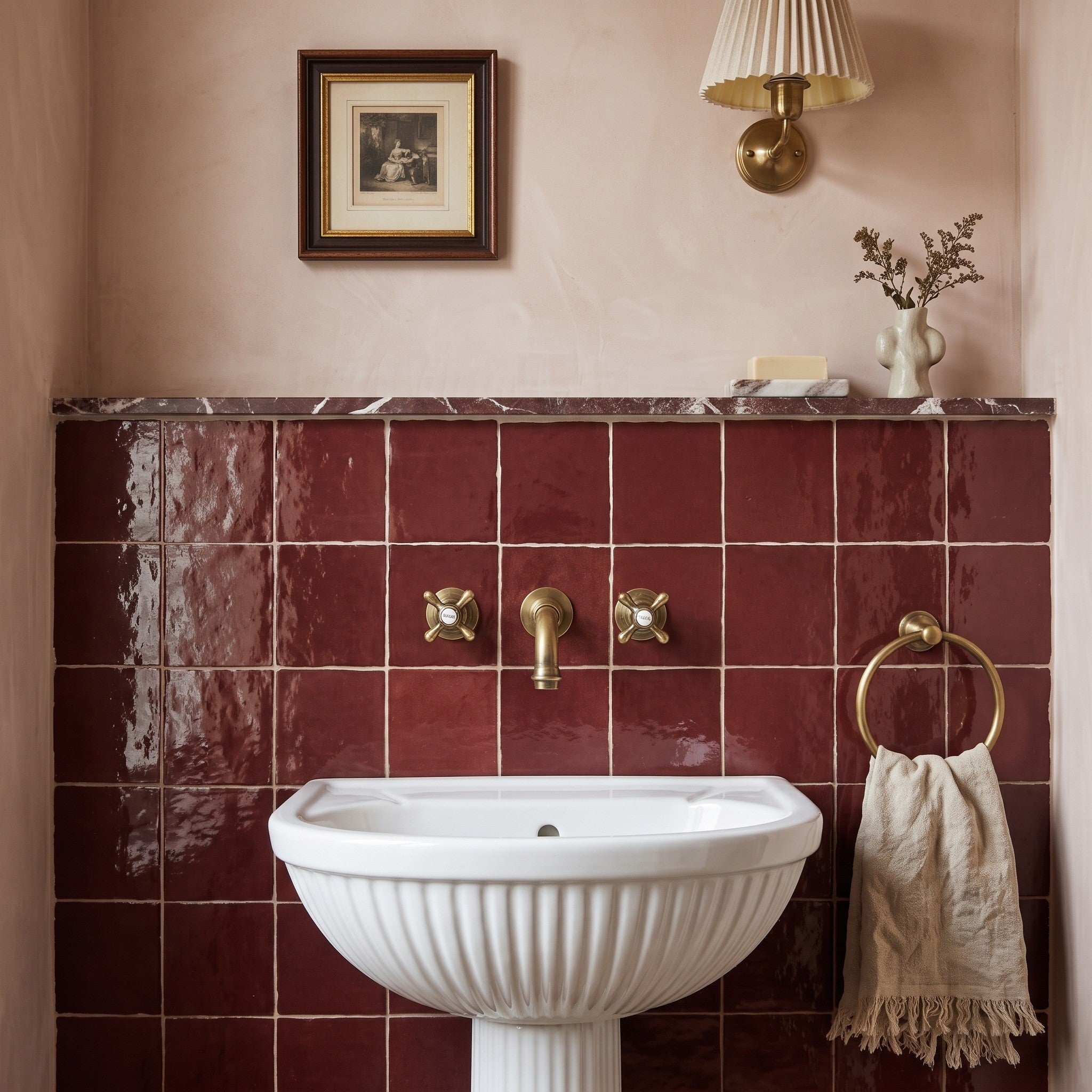 Fez Ruby wall tiles, glossy burgundy square tiles on a bathroom wall behind a white pedestal sink with brass wall taps and