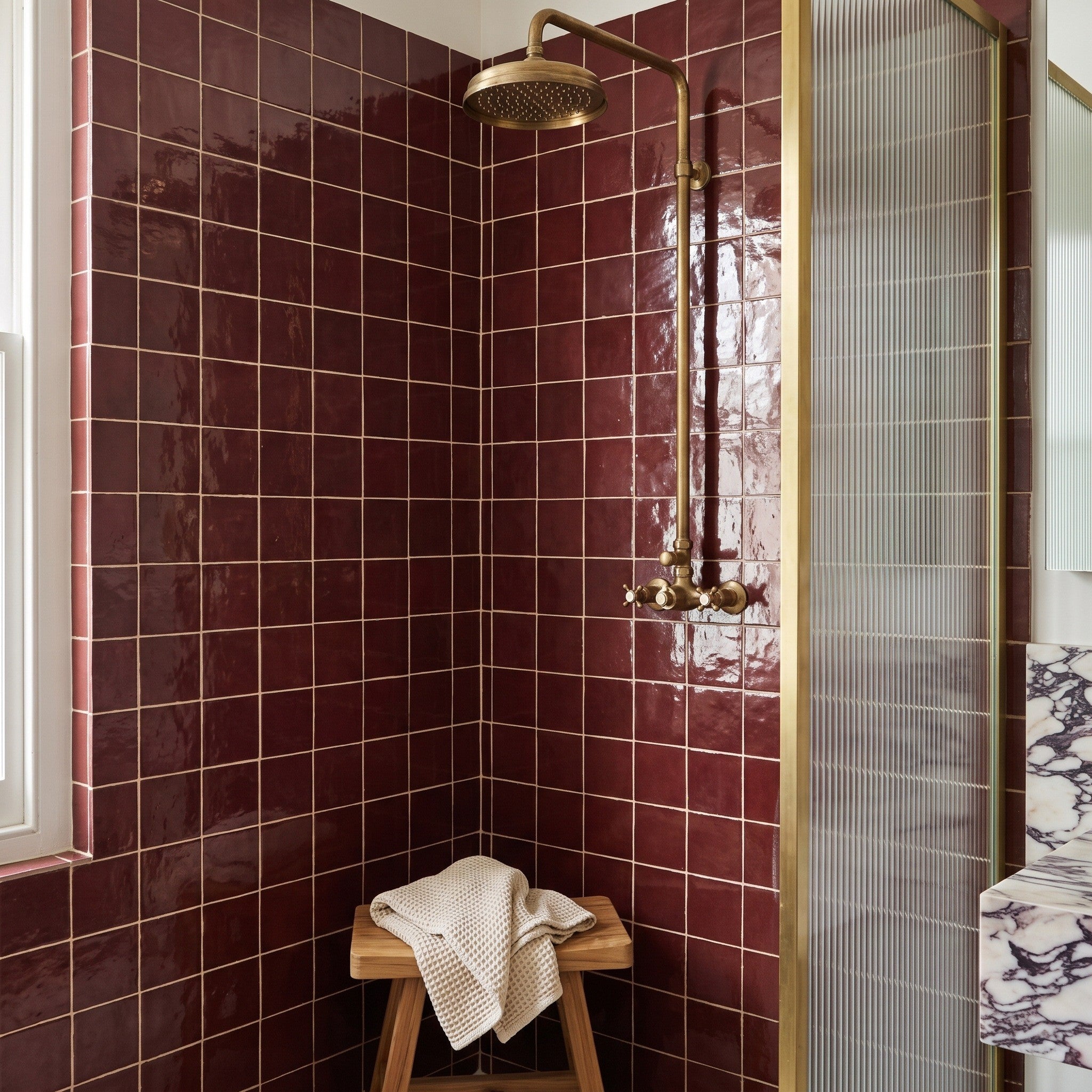 Fez Ruby wall tiles Fez Ruby wall tiles lining a shower corner with brass fittings, glossy burgundy square tiles with pale